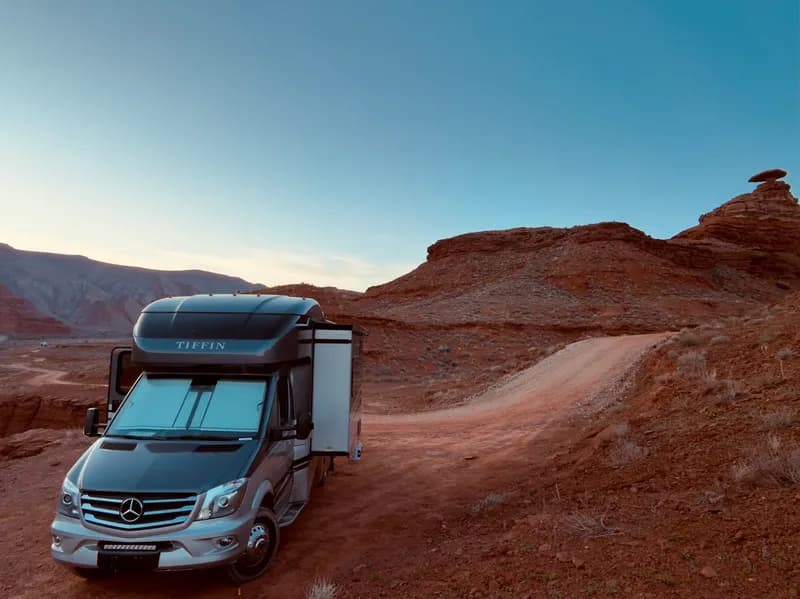 Our Class C motorhome parked on a dirt road beneath Mexican Hat Rock in Utah